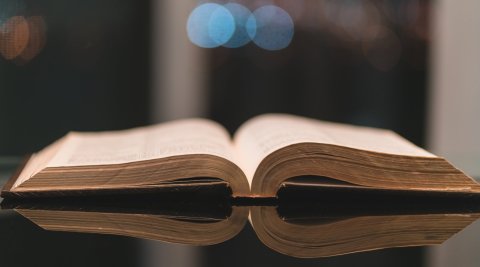 Bible open on table, blurry dark background