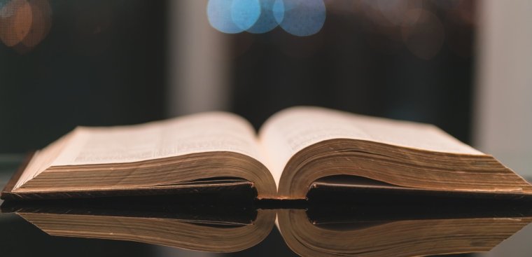 Bible open on table, blurry dark background